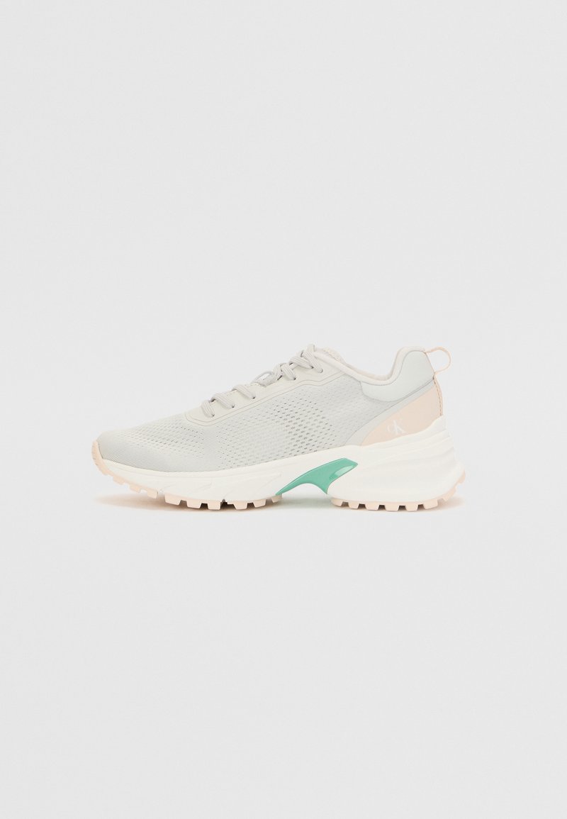 Lichtgrijze sportschoen met bovenkant van mesh, crèmekleurige rubberen zool, teal accent en gestructureerde detailing. Heeft een ronde neus en vetersluiting.