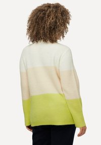 Den stickade koftan har en färgblockdesign i kräm, beige och limegrön, med en avslappnad passform och textilstruktur. Långa ärmar och rund halsringning.