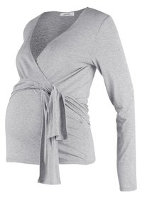 Gray, long-sleeve wrap top made of soft jersey fabric. Features a V-neck and a tied waist detail, designed to accommodate a growing belly.