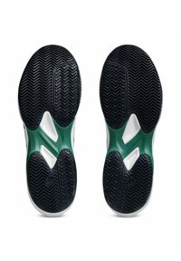 Suela de zapato deportivo con un patrón de goma negra, acentos verdes y una entresuela blanca. Presenta ranuras texturizadas para tracción.