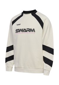 Hanorac crem cu dungi negre pe umeri și mâneci, logo-ul „SWARM INTERNATIONALS” negru și roz în față, și text mic „hummel” în stânga sus.