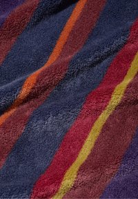 Gestreepte handdoekenstof in diep marineblauw, burgundy, oranje en geel. Zachte textuur met opvallende, ongelijkmatige strepen van verschillende breedtes.