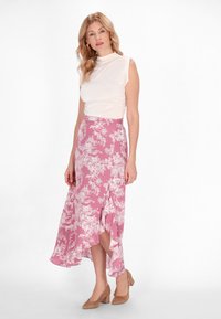 Fustă florală roz cu margine volan, asortată cu un top ajustat, de culoare deschisă. Materialul pare moale, cu un ușor luciu.