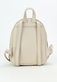 Zaino in pelle beige con finitura testurizzata, forma arrotondata, doppie spalline e manico superiore per una facile portabilità.