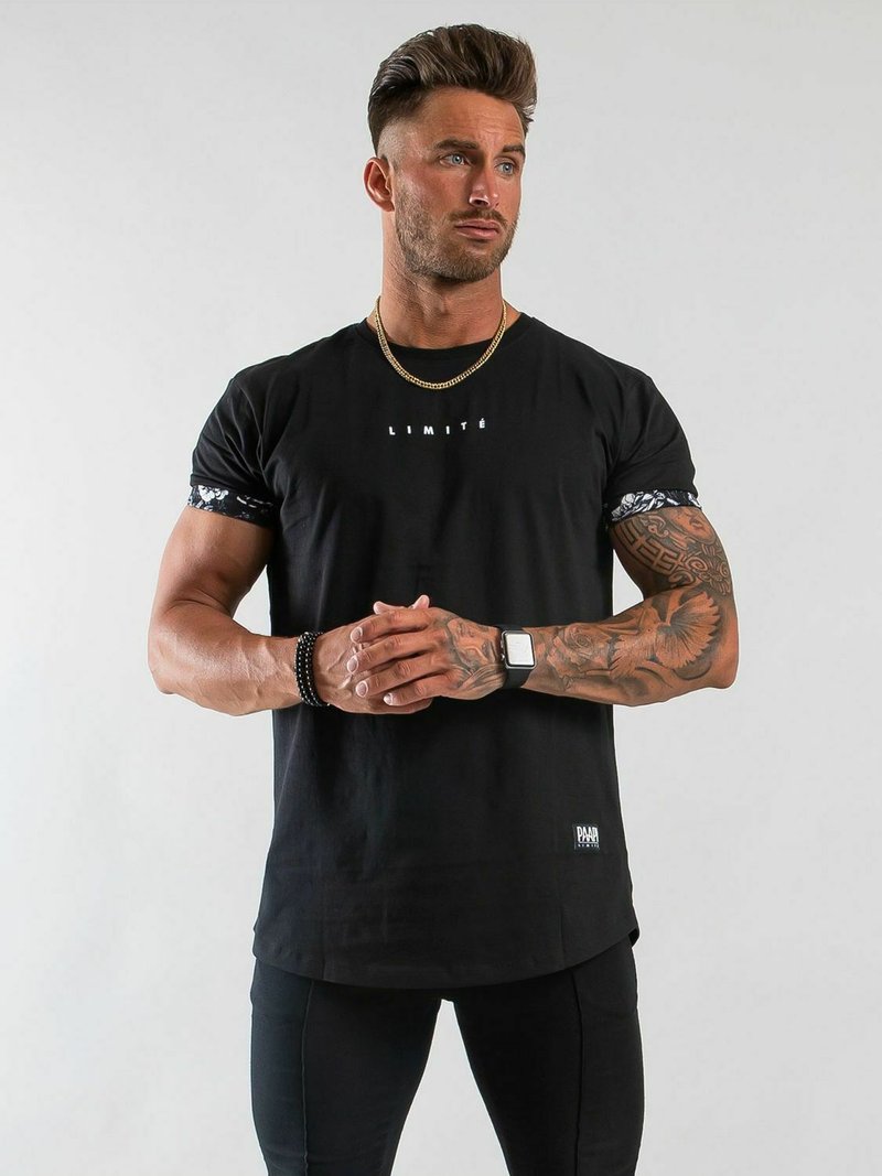 Svart t-shirt med korta ärmar, med en vit "LIMITÉ" grafik, mönstrade accenter vid ärmsluten, och rak nederkant.