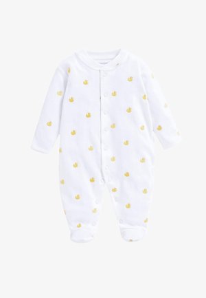 Lachende baby met rood haar die ligt op een grijze deken, gekleed in witte voetjespyjama met gele eendjesprint.