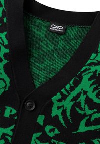 Cardigan verde e nero con un design a stampa animale testurizzato, scollo a V e bottoni neri. L'etichetta indica "PROPAGANDA."