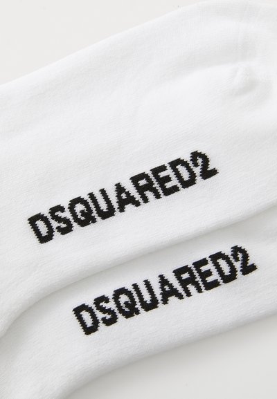 Hvite stoffsokker med svarte "DSQUARED2"-logoer brodert på hvert par mot en hvit bakgrunn.