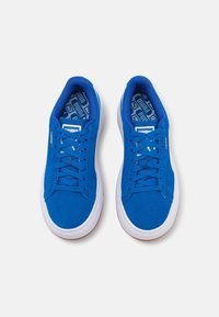 Paire de baskets Puma bleues avec semelles et lacets blancs, vues de dessus sur un fond clair uni.