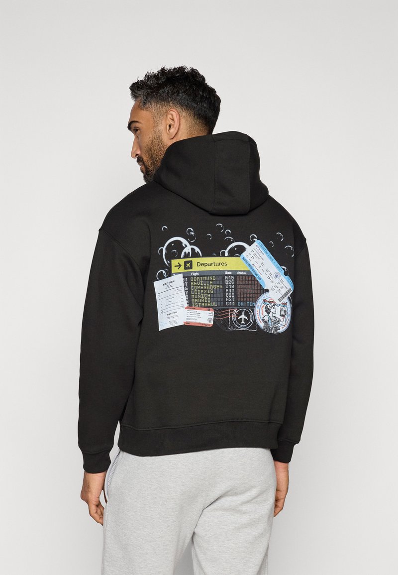 Black hoodie featuring a graphic design of departure tickets and airport signage on the back, surrounded by bubble-like elements.