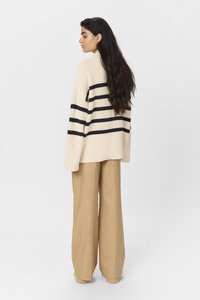 Helebeez, suuruse poolest oversized, beez värvi sviiter tumesiniste triipudega, ribakujuline tekstuur. Kombineeritud kõrge vöökohaga, laiemate khaki pükstega.