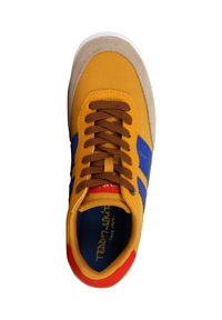 Chaussure de sport jaune avec des rayures bleues et des lacets marron. Dispose d'un embout en daim texturé, d'accents rouges et d'une doublure intérieure bleue.