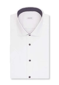 Chemise blanche plissée avec des boutons foncés et un col blanc bordé d'un motif à pois noir et blanc.