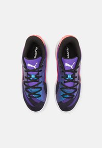 Paarse en zwarte sportieve schoenen met een gestructureerde bovenkant van stof, dynamisch ontwerp, zwarte veters en roze accenten; bevat een witte zool.