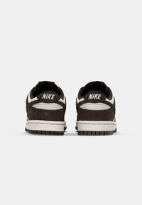 Pár černobílých tenisek Nike zobrazených ze zadní strany, s bílým logem Nike na patě a silnou bílo-černou podrážkou.