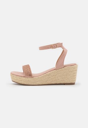 Różowe sandały na klinie z zamszu, z paskiem wokół kostki i klamrą, na platformie z tkanego juty, z odkrytymi palcami i teksturowanym paskiem z przodu.