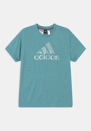 Turfowa koszulka z krótkim rękawem wykonana z teksturowanej tkaniny, z dużym, odbijającym światło logo Adidas umieszczonym na środku z przodu.