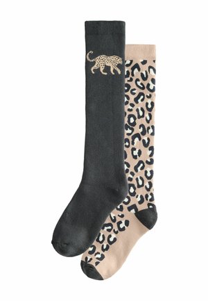 Schwarze, knielange Socke mit einem Leopardenmuster oben; beigefarbene Socke mit einem schwarzen Leopardenprint. Beide sind aus weichem Stoff hergestellt.