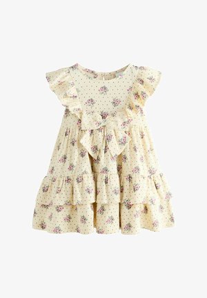 Rochie crem pentru copii mici, cu imprimeu floral roz, buline negre, mâneci cu volane, fustă în straturi și fundă mare pe piept.