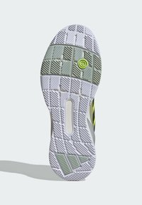 White sneaker sole with textured grip, featuring green accent with a circular design and a cutout. Various tread patterns for traction.