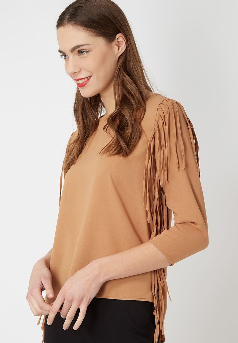 Top marrón con mangas de tres cuartos que presenta flecos texturizados en los hombros, fabricado en un tejido suave, con un corte holgado y relajado.