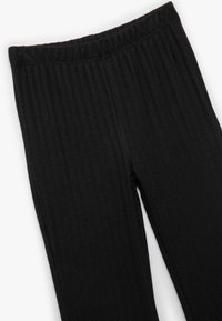 Leggings negros de canalé con una cinturilla elástica, que presentan una textura suave y un diseño ajustado. Aptos para uso casual.