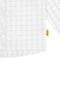 Camicia bianca con motivo a quadri blu, tessuto di cotone, colletto con bottoni e un'etichetta gialla. Orlo arrotondato e maniche lunghe con dettagli sui polsini.