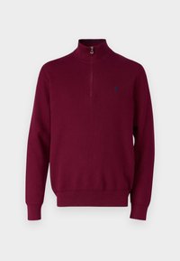 Burgunderfarbener Strickpullover mit einem halben Reißverschluss am Kragen. Mit geripptem Saum und Bündchen sowie einem kleinen blauen Logo auf der Brust. Weiche Textur.