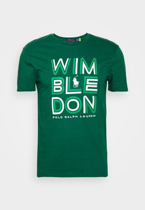 Grünes T-Shirt mit kurzen Ärmeln, auf dem "WIMBLEDON" in großen weißen und grünen Buchstaben steht, mit dem Polo Ralph Lauren Logo und Text darunter.