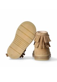 Stivaletti alla caviglia in suede beige morbido con dettagli in frange, suola in gomma e punta rotonda. La suola presenta scanalature orizzontali per una migliore aderenza.