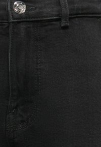 Černé džíny z denimu s klasickým pětipocketovým designem, s kovovým knoflíkem a prošíváním na pase a švech.