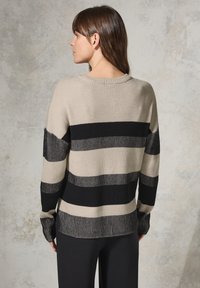 Maglione a maglia con strisce orizzontali beige e nere, texture a coste, scollo rotondo e maniche lunghe con polsini aderenti.