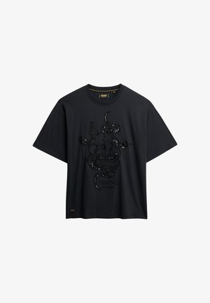 T-shirt noir à manches courtes avec un graphisme orné de paillettes représentant un crâne de vache enlacé par un serpent, accompagné du texte « Superdry Los Angeles ».