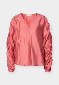 Κοραλλί σατέν μπλούζα με V-λαιμόκοψη, κούμπωμα με κουμπιά και φουσκωτά μανίκια. Ομαλή υφή με άνετη γραμμή και διακριτική γυαλάδα.