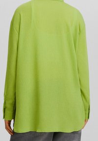 Camicetta verde, textured a maniche lunghe con una vestibilità ampia e polsini con bottone, caratterizzata da un colletto classico e un orlo dritto.
