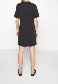 Svart bomullsklänning med kort ärm, rund halsringning, avslappnad passform och knälång fåll. Enkelt utförande utan mönster eller dekorationer.
