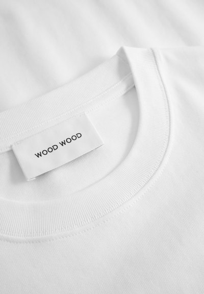 Balta medvilninė marškinėlių su apvalia iškirpte, suiamegiančia minkšta tekstūra ir etikete, kurioje juodu tekstu parašyta "WOOD WOOD".