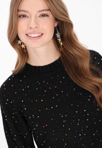 Fekete pulóver színes, szórt gyöngyökkel, bordázott nyakkivágással. Figyelemfelkeltő, csillagformájú fülbevalók különböző színekben.