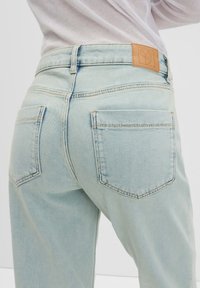 Hellblaue Denim-Jeans mit hoher Taille, zwei Gesäßtaschen, dezentem Nähen und einem Lederpatch am Bund mit einem Logo.