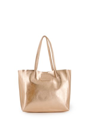 Skinnende metallisk guldtote taske med to lange håndtag og et lille rektangulært mærke tæt på øverste center.