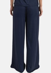 Marineblauwe wijdere broeken gemaakt van zachte, lichte stof. Heeft een elastische tailleband voor comfort en een relaxte pasvorm. Gladde textuur.
