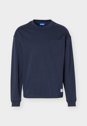 Camiseta de manga larga y cuello redondo de color azul marino con bolsillo en el pecho, puños acanalados y una pequeña etiqueta blanca de la marca cerca del dobladillo.