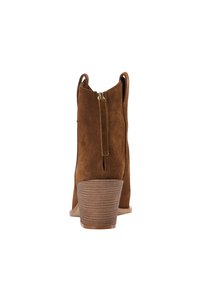 Stivali alla caviglia in suede marrone con tacco impilato di media altezza, dotati di cerniera posteriore e anelli di trazione per un facile indossamento. Silhouette curva e texturizzata.