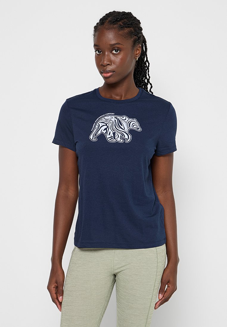 T-shirt col rond marine en coton, avec un graphique d'ours blanc présentant des motifs linéaires complexes sur la poitrine. Manches courtes, coupe décontractée.
