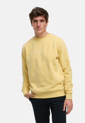 Sudadera de algodón amarilla con cuello redondo y mangas largas, que presenta un pequeño logo en blanco en el pecho y puños y dobladillo acanalados.