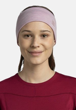 Light pink fabric headband made of soft material, featuring a solid texture and a small logo tag. Worn by a smiling person in a maroon shirt.