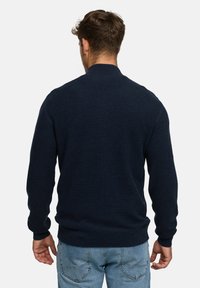Marineblauer Strickpullover mit langen Ärmeln und hohem Kragen, ausgestattet mit einem strukturierten Gewebe sowie gerippten Bündchen und Saum.