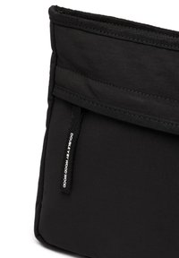 Mustmust kangas, millel on sile tekstuur, ülemise sulgemisega ja sildiga, millel on kirjas "DOUBLE BY WOOD WOOD". Lihtne ristküliku kujuline. 