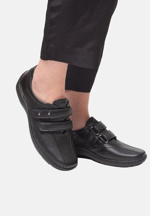 Black leather shoes featuring double Velcro straps, a rounded toe, and textured upper with a flexible sole.