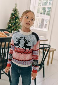 Maglione lavorato a maglia con un vivace motivo di renna in blu, rosa, rosso e nero, con collo e polsini a coste, abbinato a jeans blu.